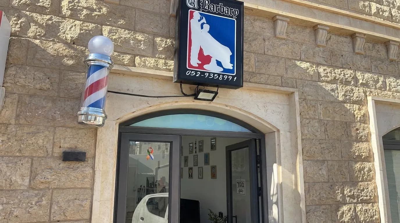 Exterior entrance of El Barbery Barber Shop with its sign and barber pole